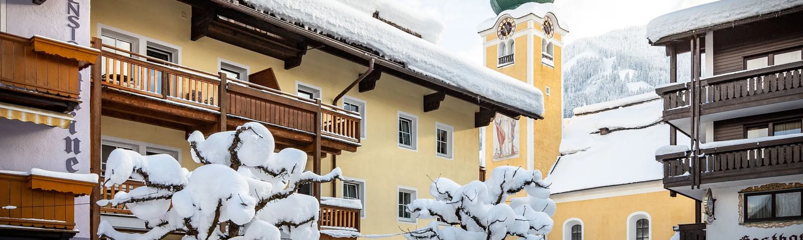 Schneebedeckte Gebäude und ein Glockenturm in einer Winterlandschaft