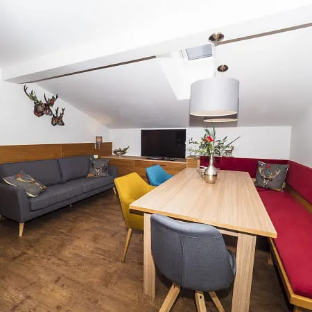 Gemütliches Interieur mit einem grauen Sofa, Holztisch und roten Sitzgelegenheiten