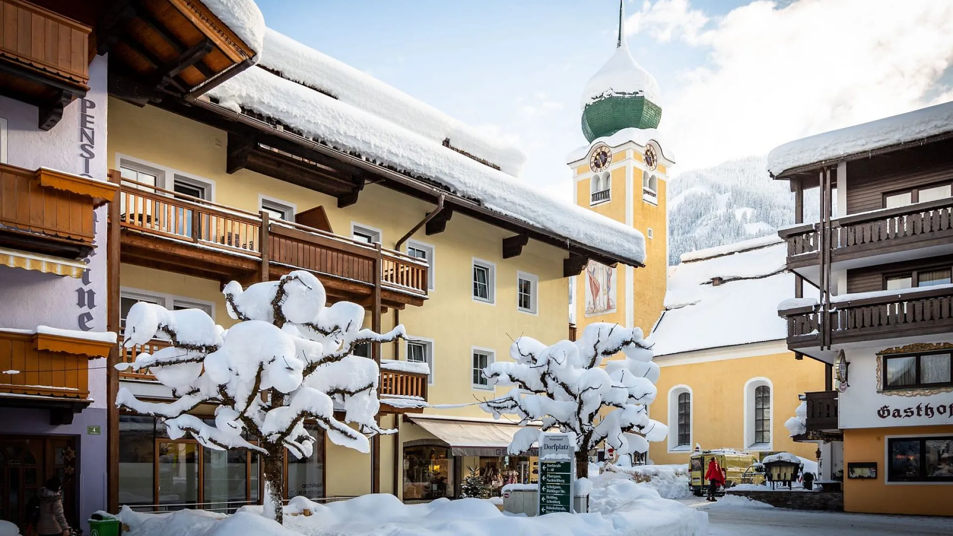 Schneebedeckte Gebäude und Bäume in einem alpinen Dorf