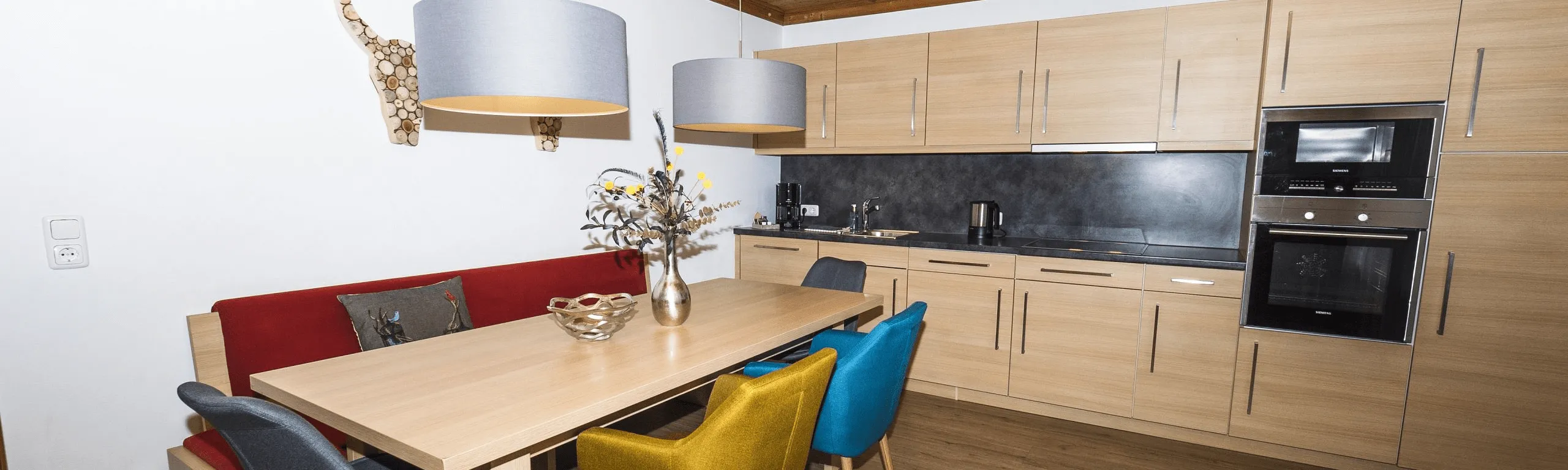 Moderne Küche mit Holzschränken und bunten Stühlen