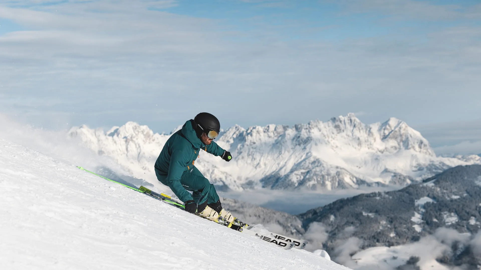 Skifahrer auf schneebedecktem Hang mit Bergen im Hintergrund