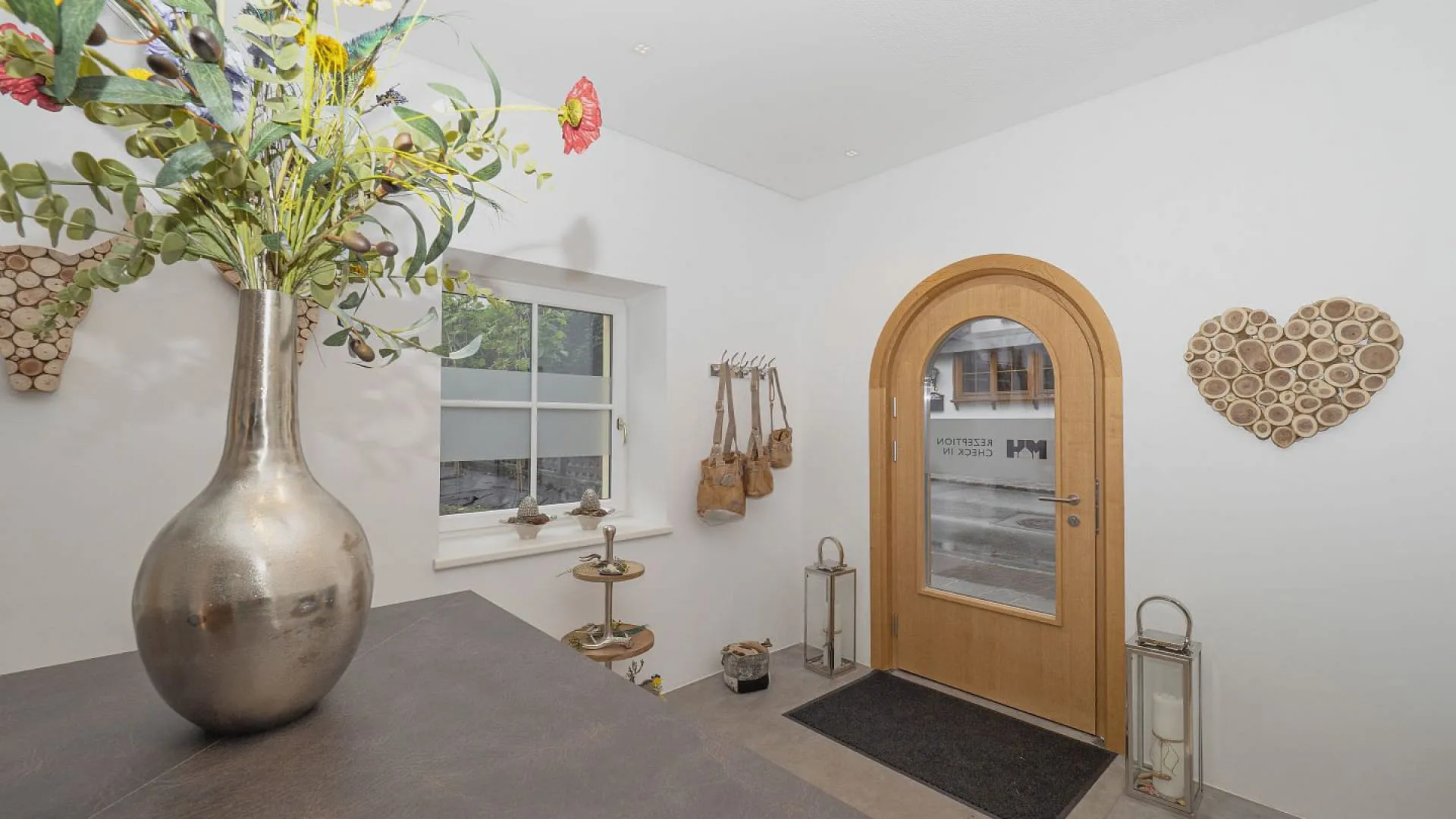 Helle Eingangshalle mit Vase und Holzhaustür.
