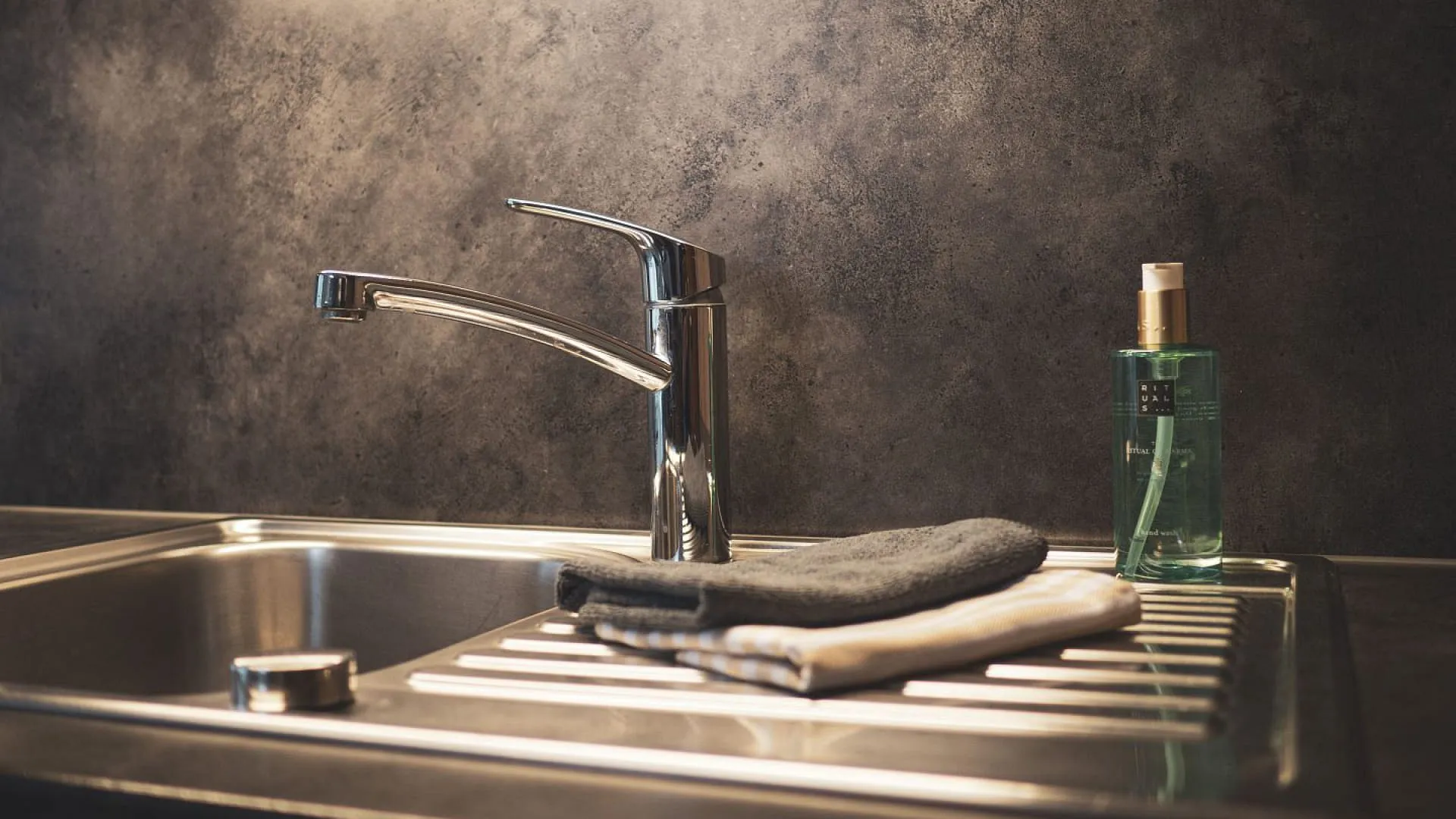 Moderne Spüle mit Wasserhahn und Handtüchern