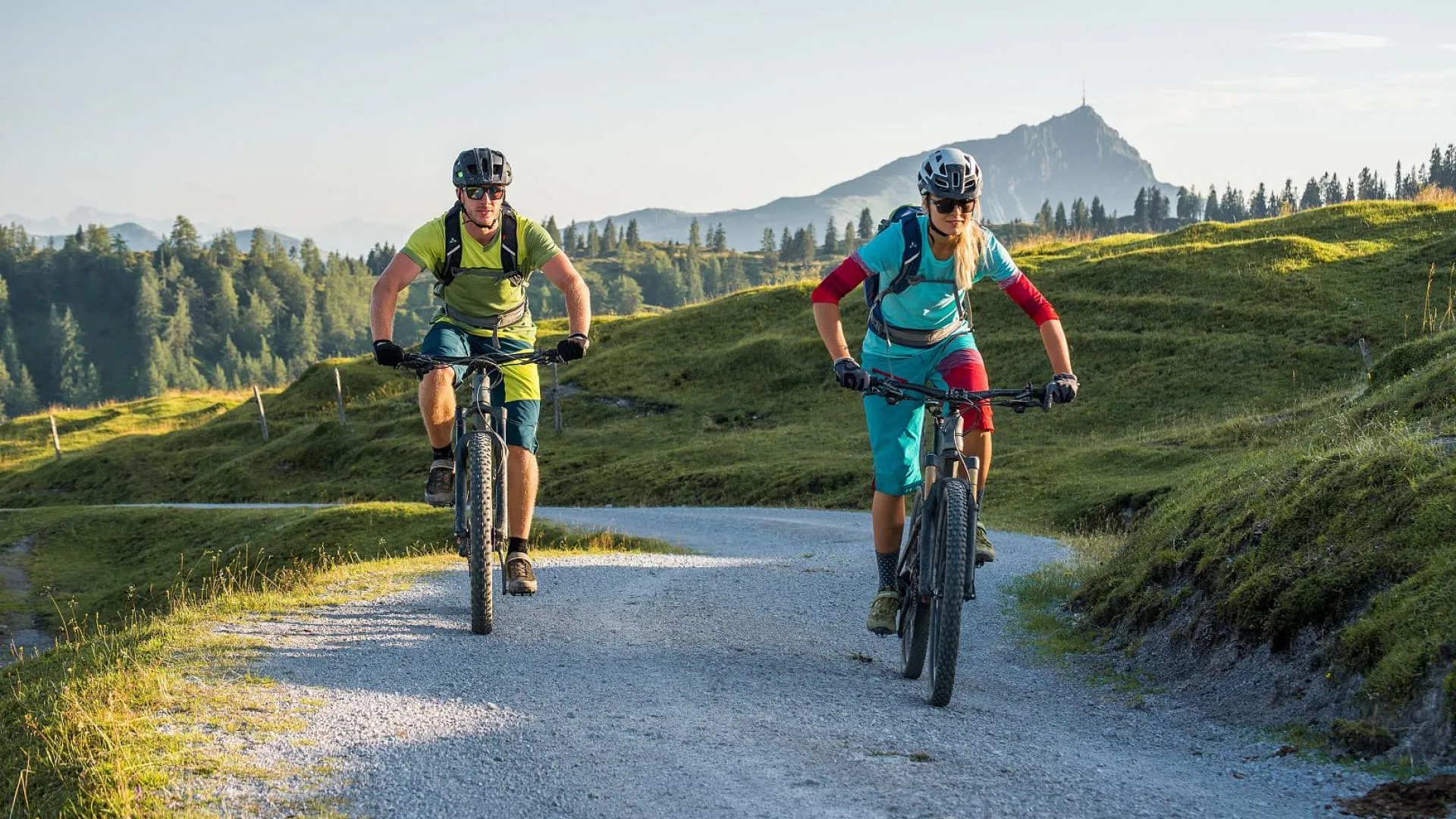 Zwei Personen fahren auf E-Bikes durch die Tiroler Landschaft.