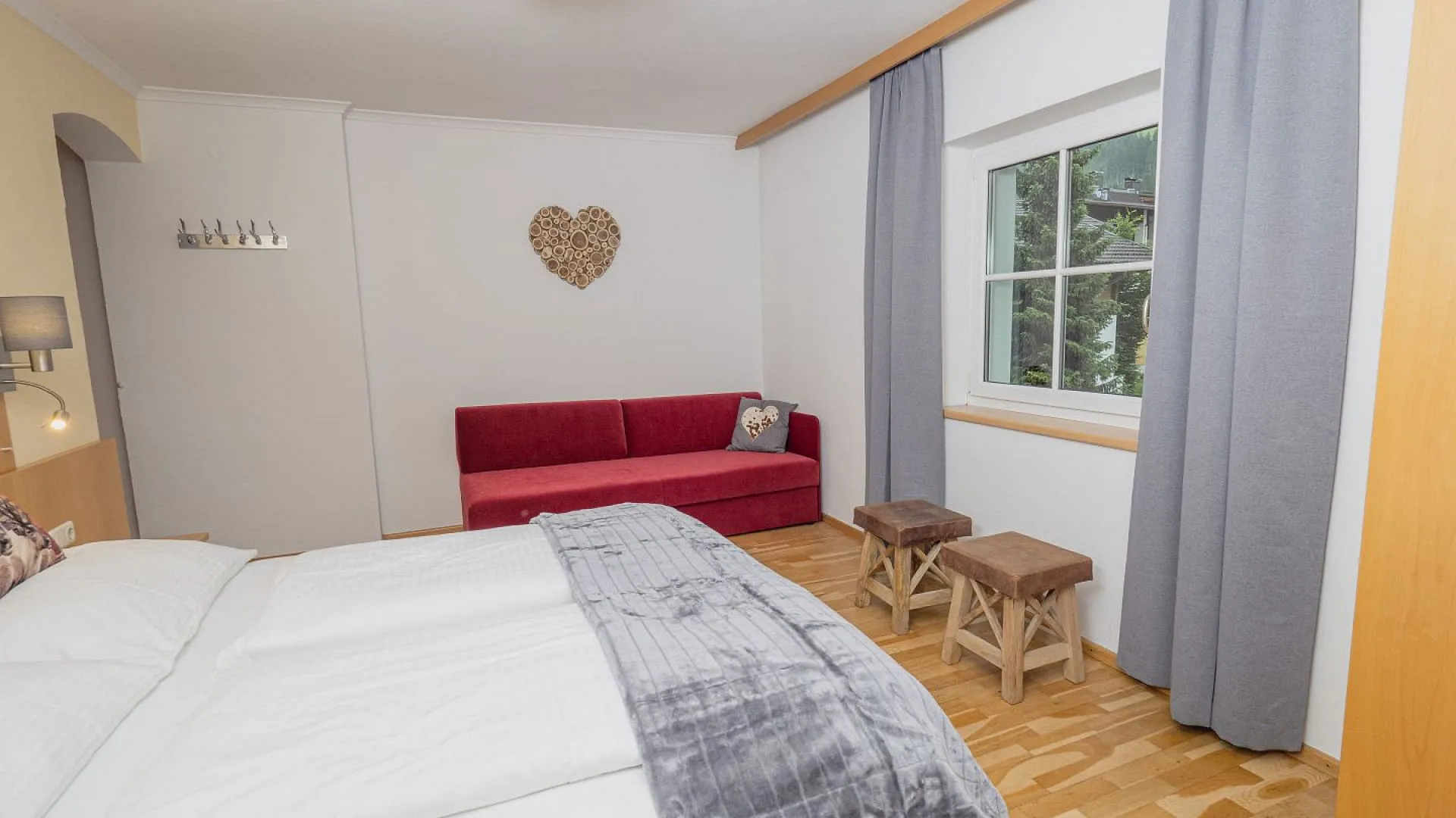 Helle Schlafzimmer mit rotem Sofa und Holzfußboden.