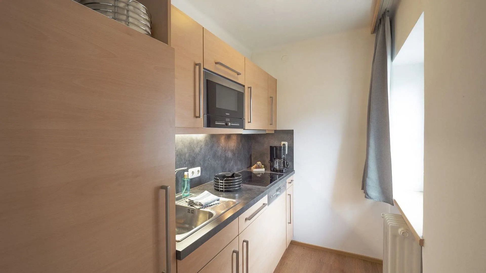 Moderne Küche mit Holzschränken und Fenstern.