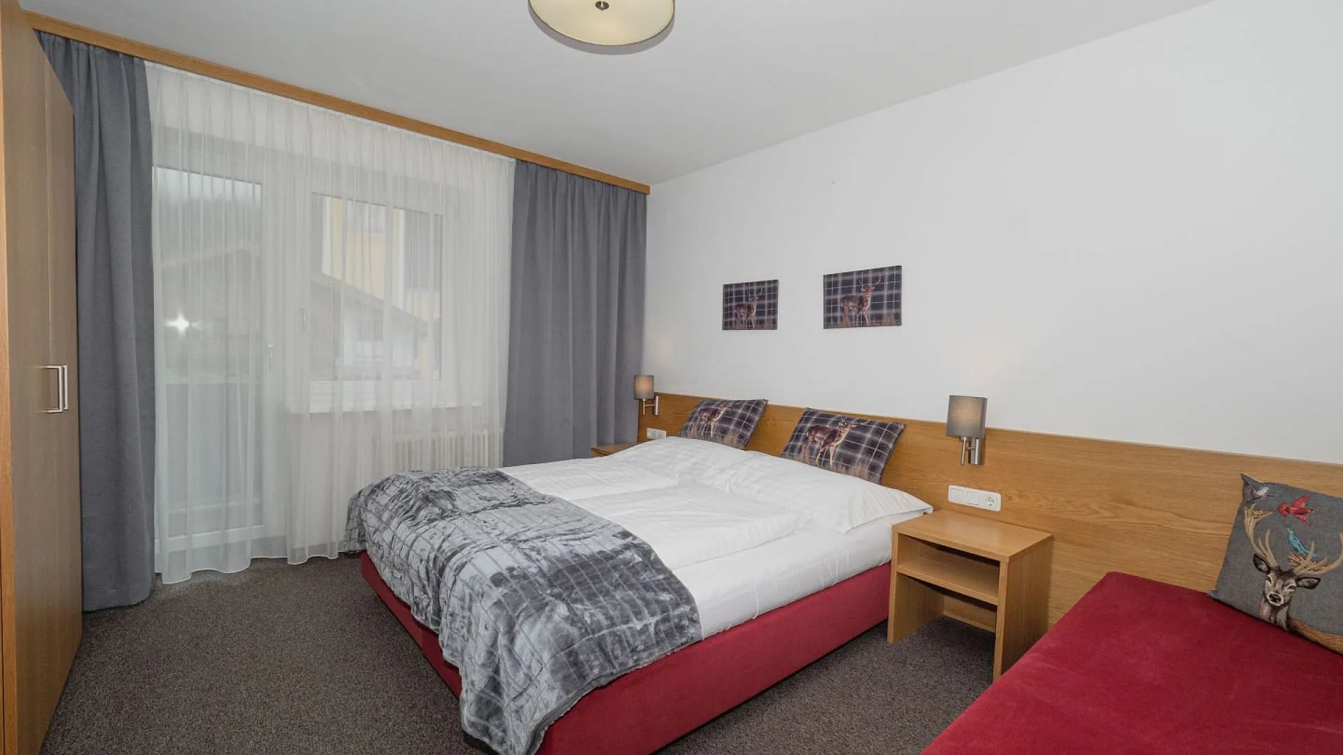 Modernes Schlafzimmer mit rotem Bett und Balkonfenster