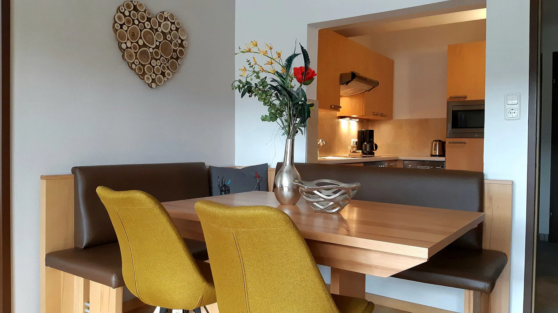 Helles Wohnzimmer mit Holz-Tisch und gelben Stühlen.
