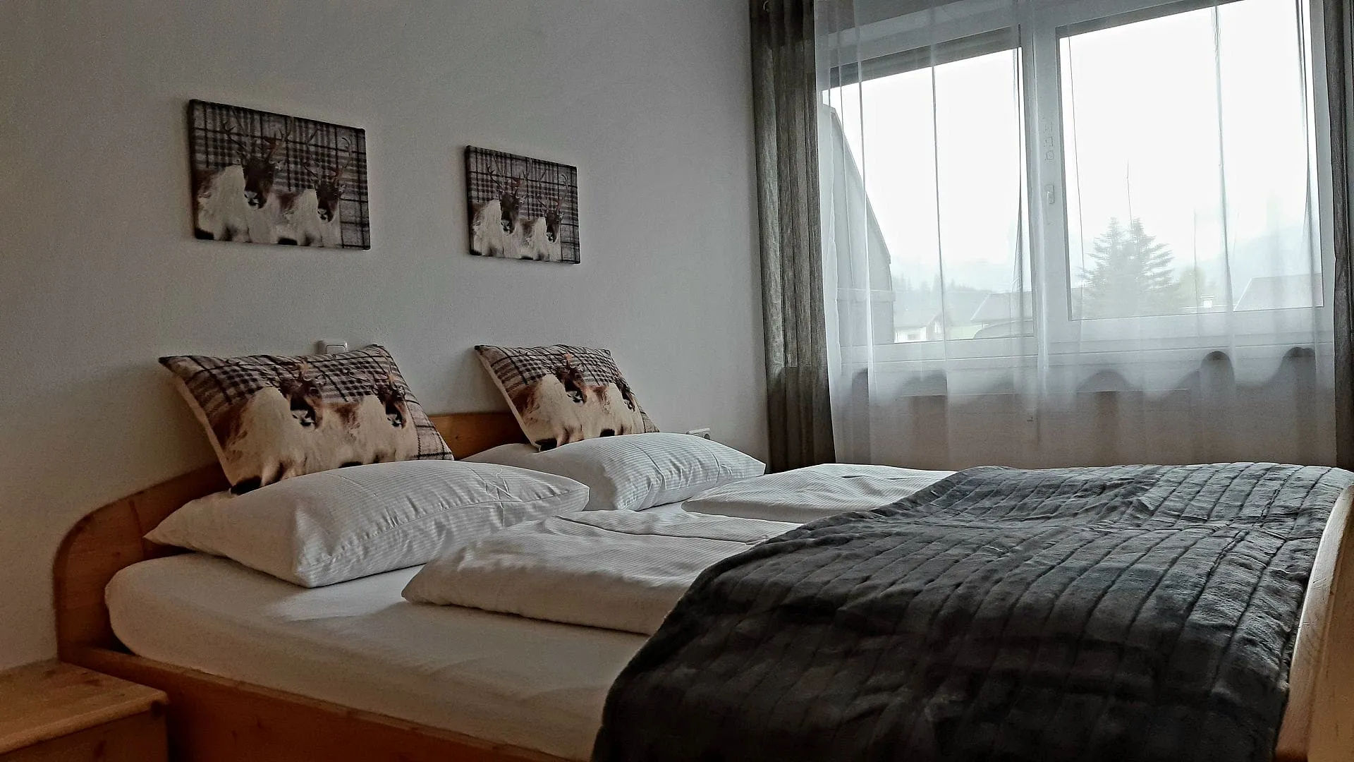 Helles Schlafzimmer mit Doppelbett und großen Fenstern.